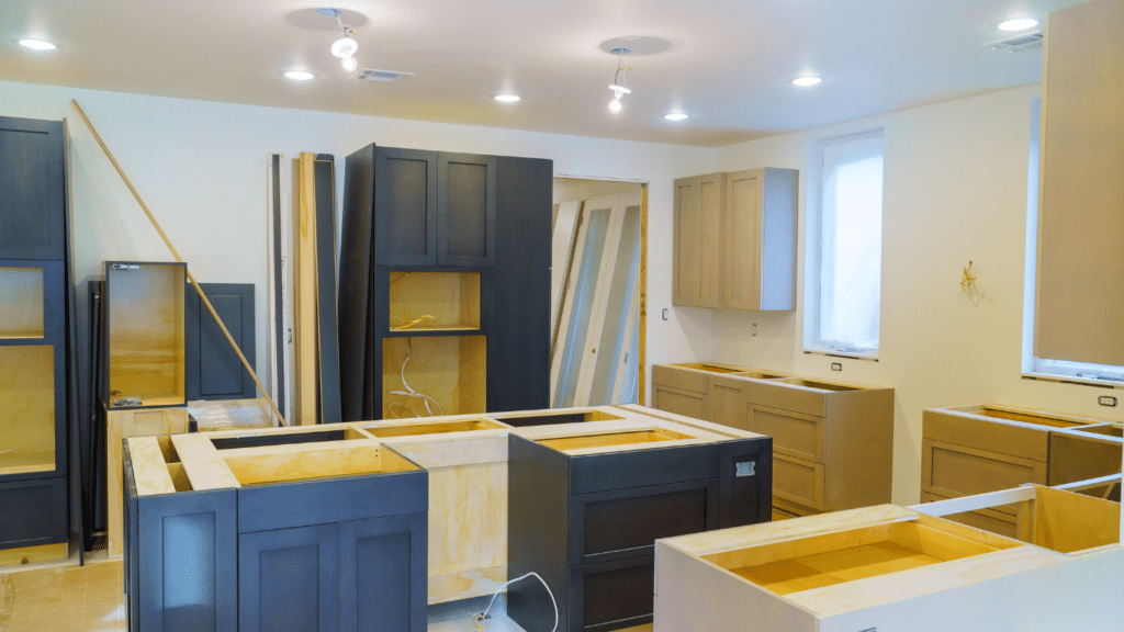 Kitchen under renovation with new dark and light wood cabinets being installed by a trusted West Seattle remodeling contractor; countertops not yet in place, and tools and materials visible around the room.